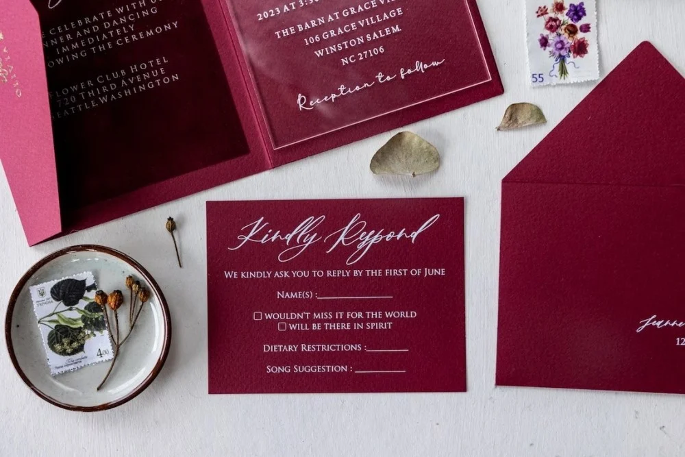 Gold foiled acrylic wedding invitation in burgundy velvet pocketfold.