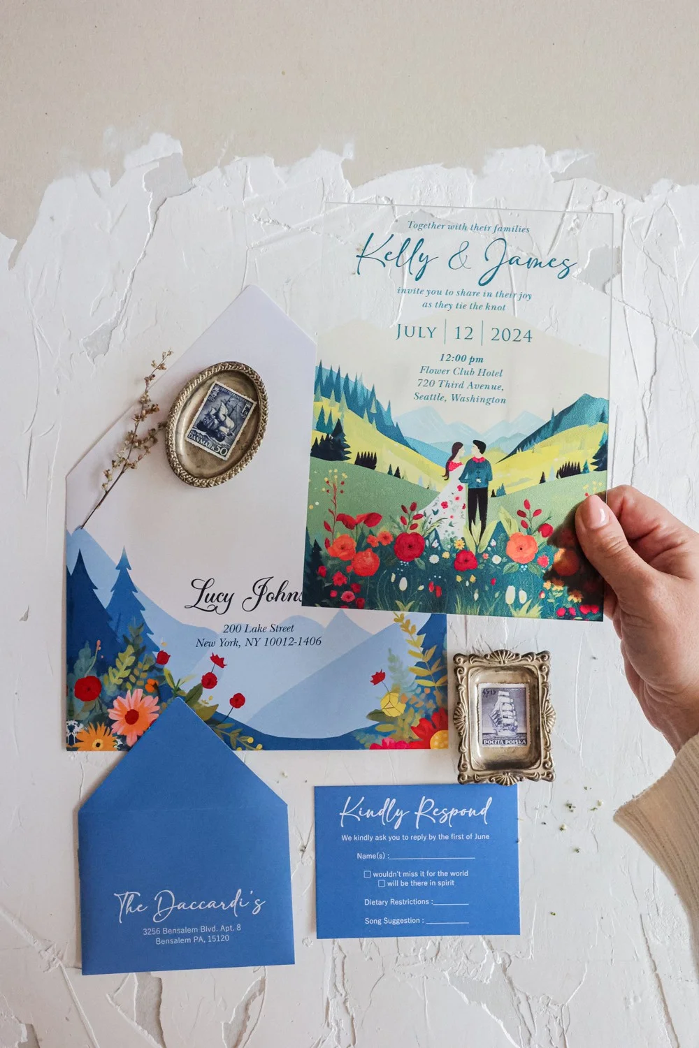 Transparent wedding invite displaying a serene mountain backdrop with colorful meadow flowers.