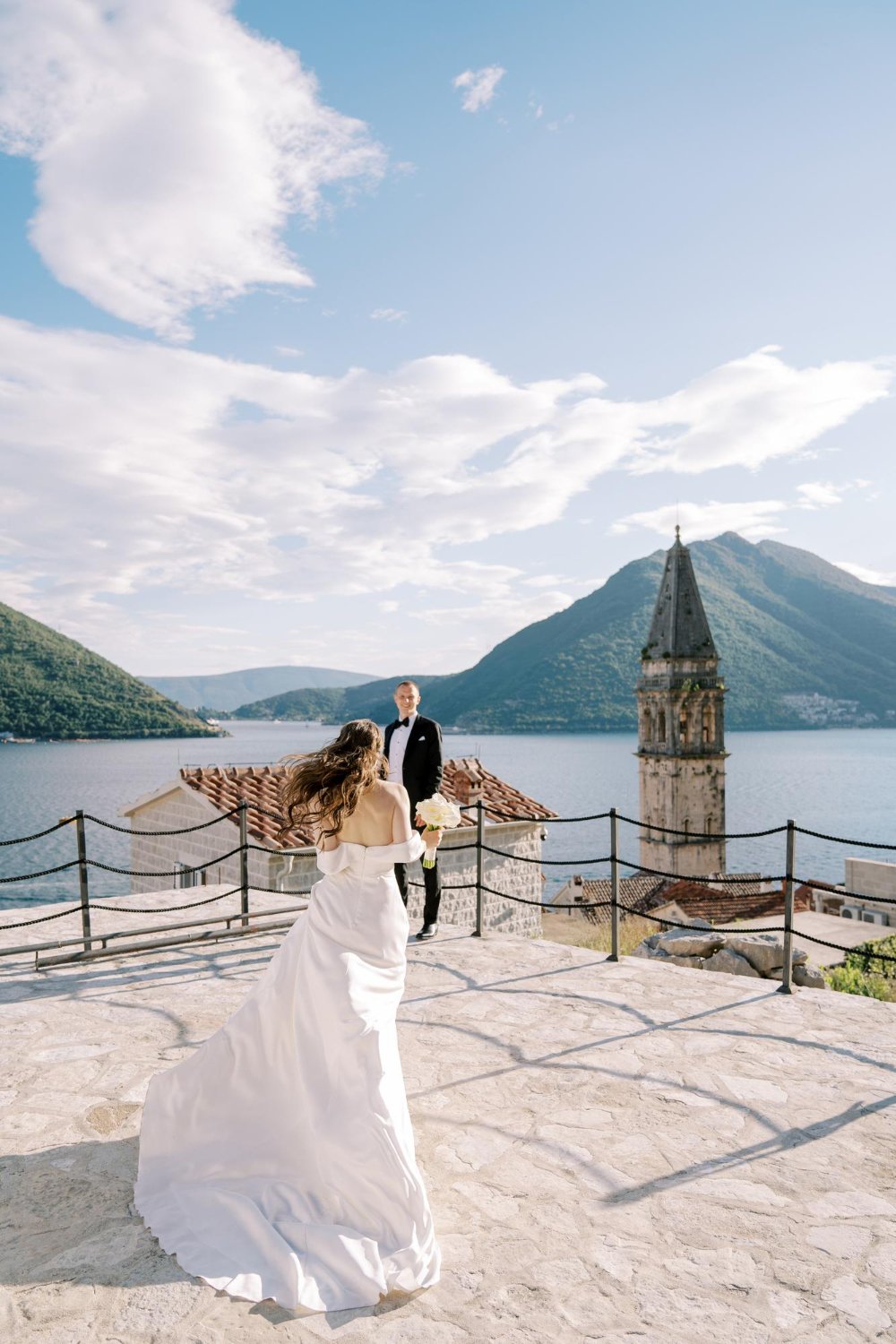 Bride runs to groom along the observation deck overlooking the belfry perast montenegro