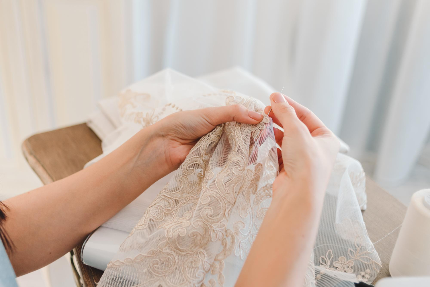an atelier or seamstress works on lace fabric sews a curtain with a needle
