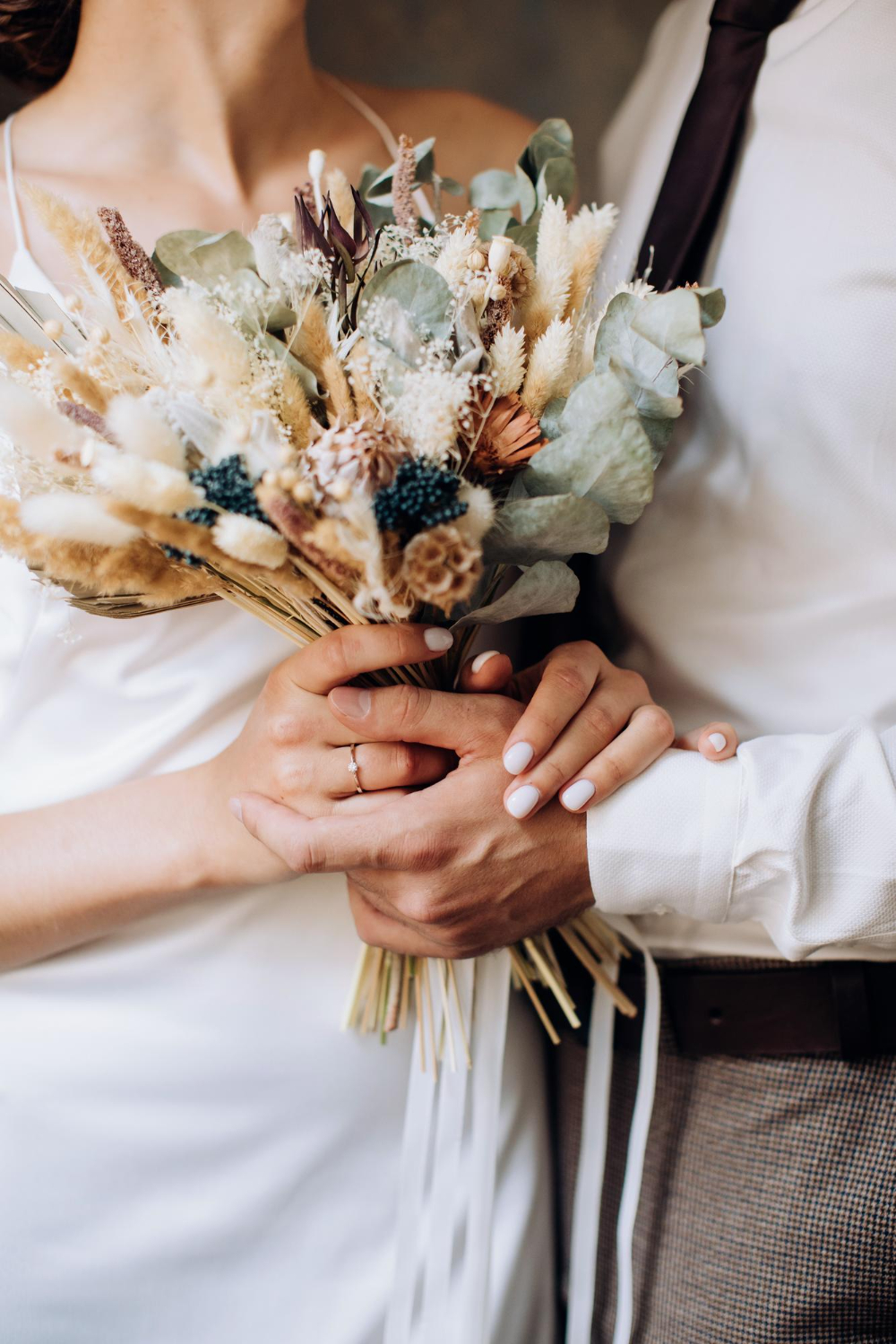 the bride and groom holds in her hands a beautiful bouquet of dried flowers in the style of boho