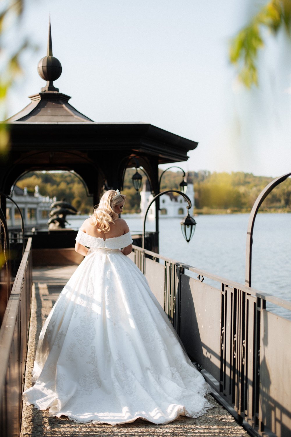 bride in a white wedding dress with a long train is standing in a green park