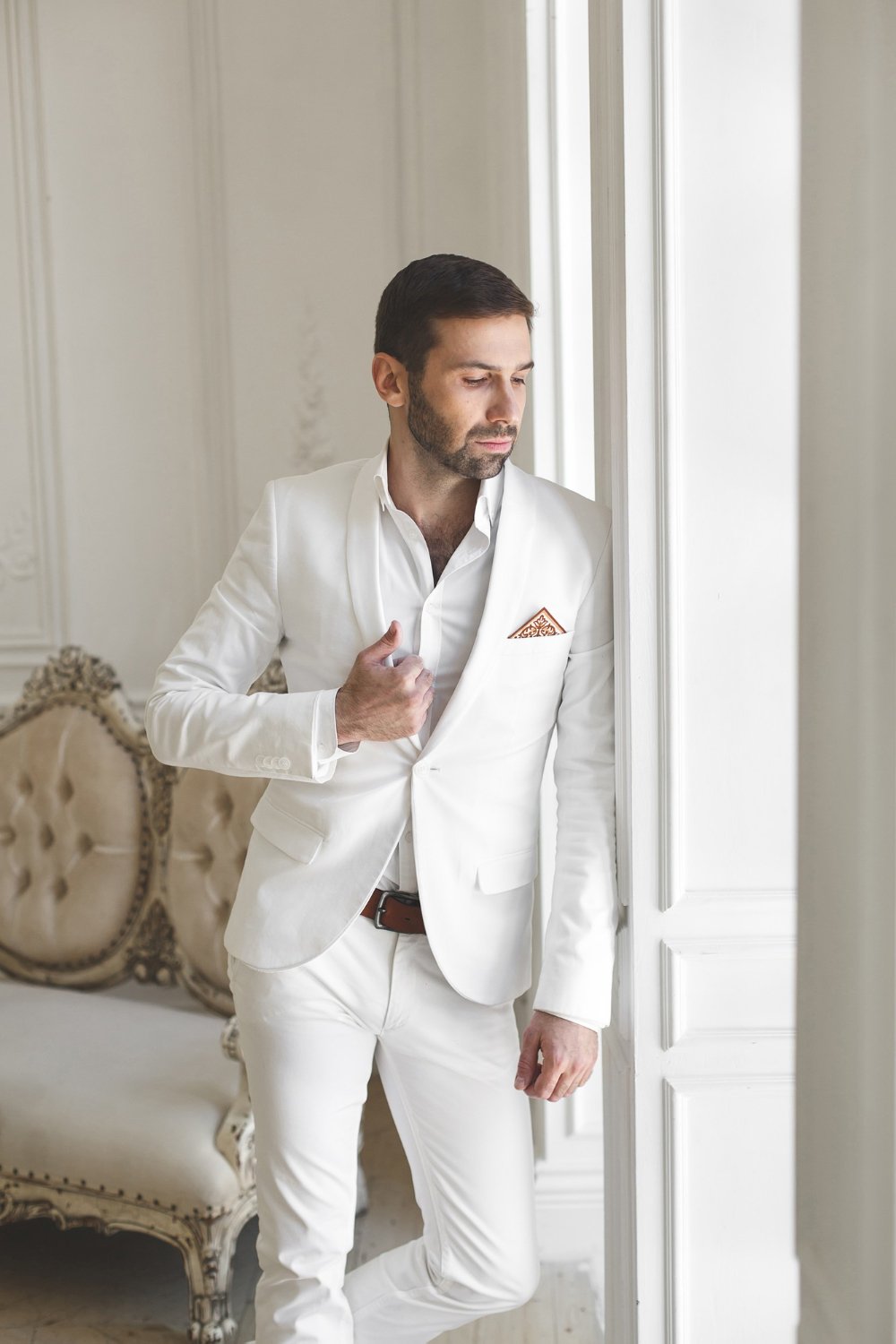 legant young handsome man with a beard in a white classic suit