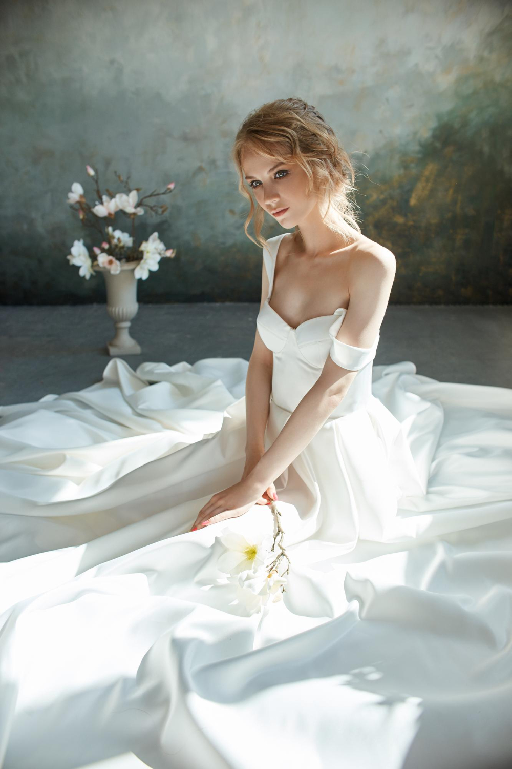 girl in a chic long dress sitting on the floor white wedding dress