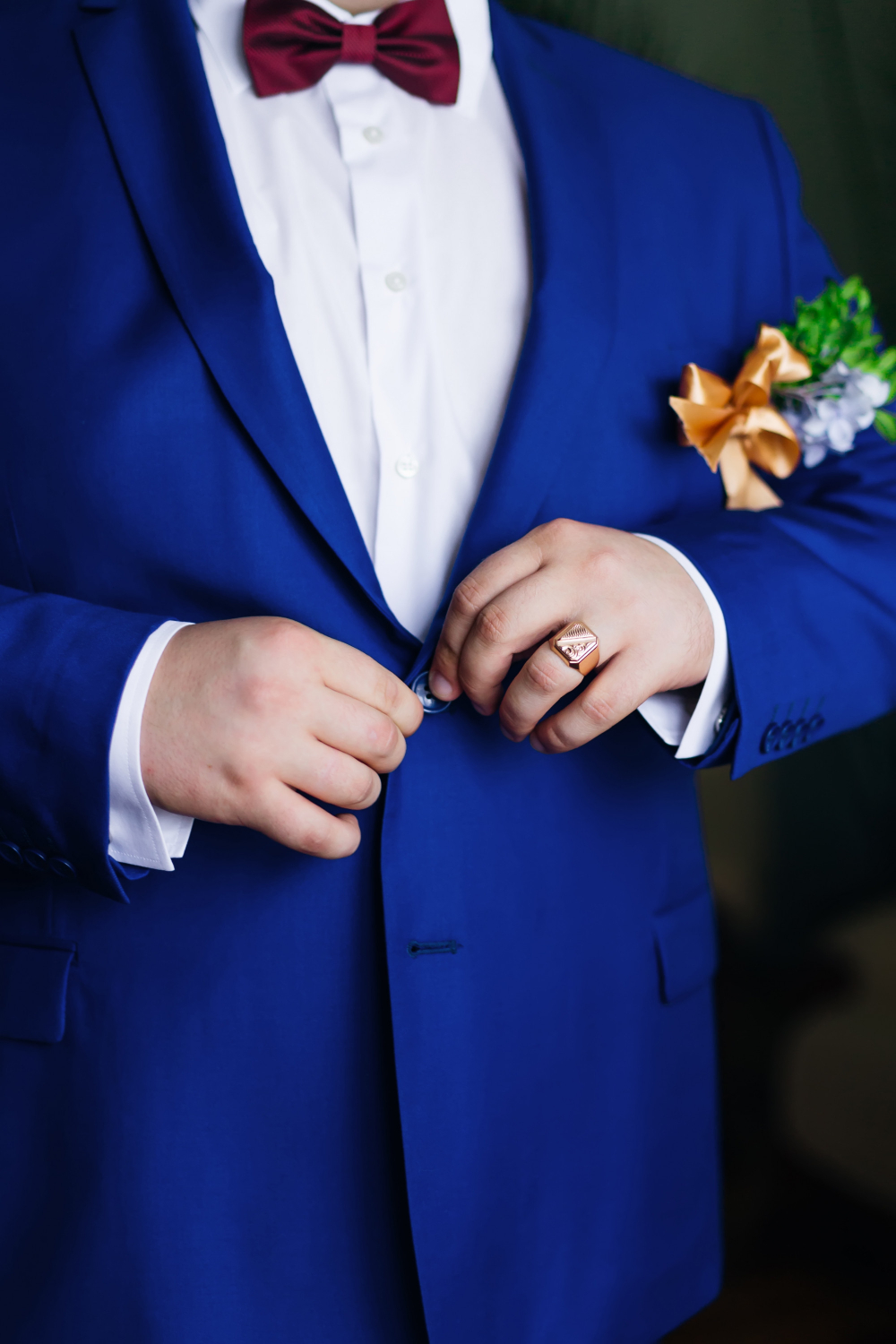 Photo groom in white shirt and stylish blue jacket with boutonniere.