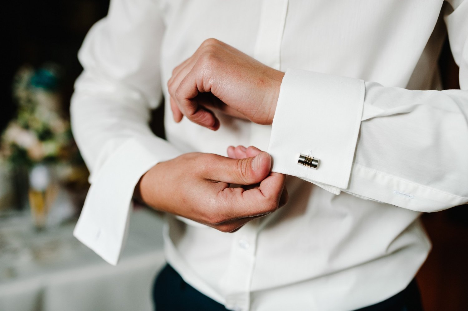handsome man buttoning cufflinks on white shirt. groom's elegant male gold cufflink