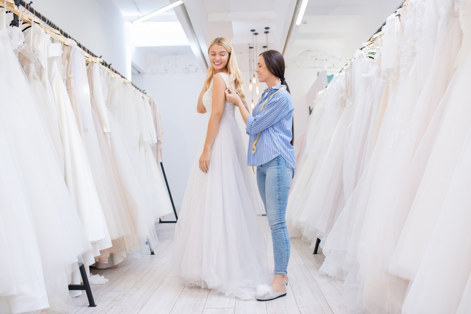 Photo shop assistant helping women to fasten dress