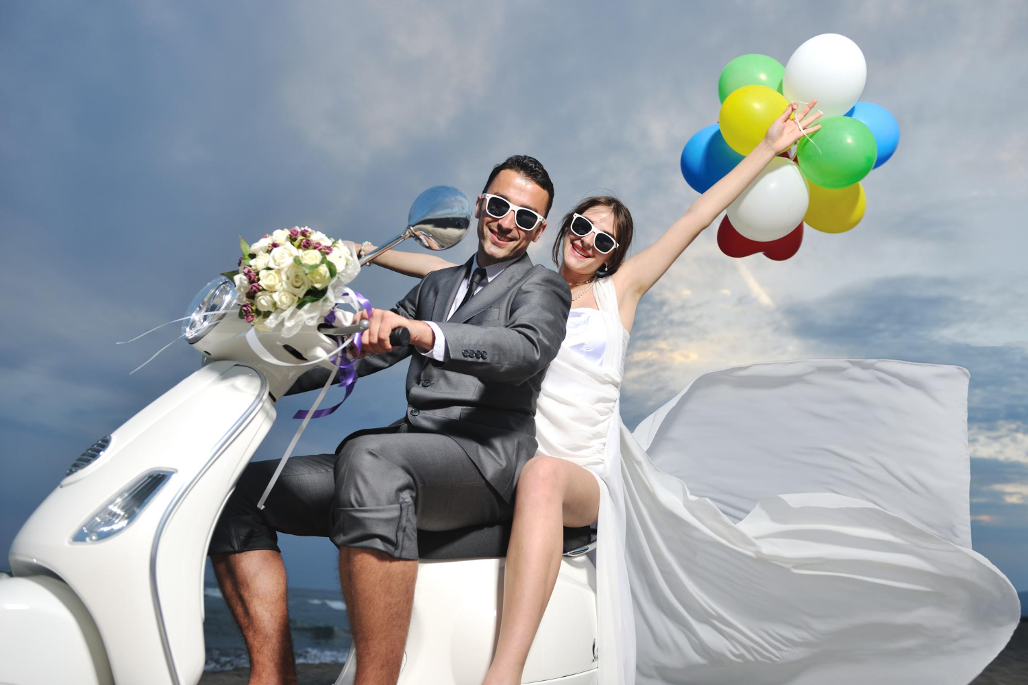 wedding sce of bride and groom just married couple on the beach ride white scooter and have fun