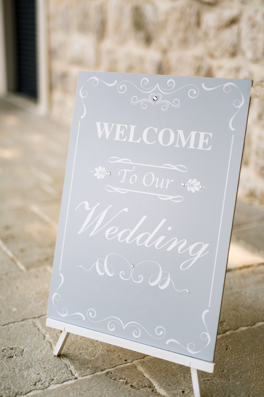 wooden easel with inscriptions stands in front of an ancient building inscription welcome to our wedding